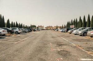 Parking gratuit en bord de mer à Pise avec voitures garées et paysage urbain toscan en arrière-plan